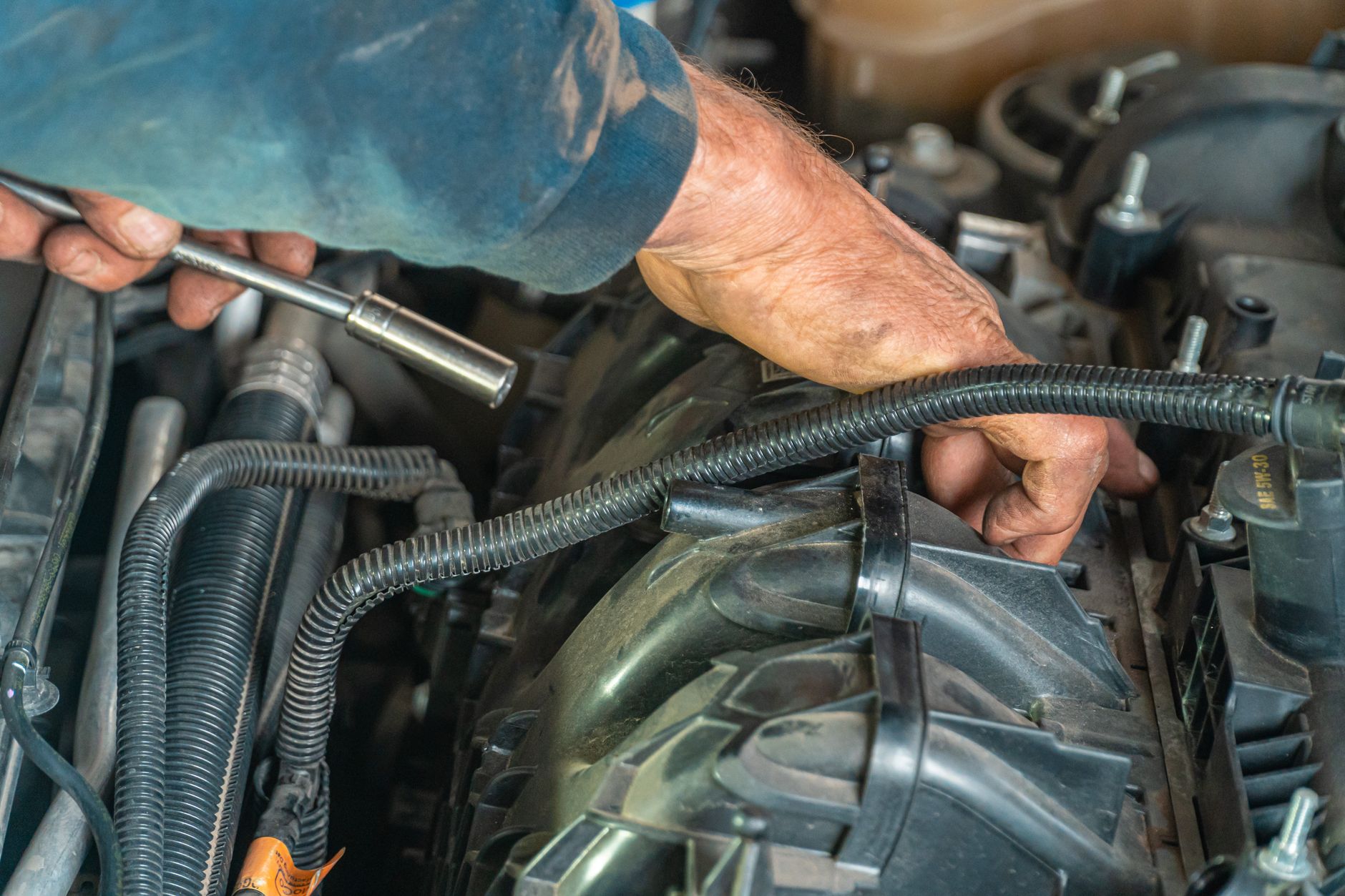 Mécanicien vérifiant un tuyau moteur sous le capot d'une voiture