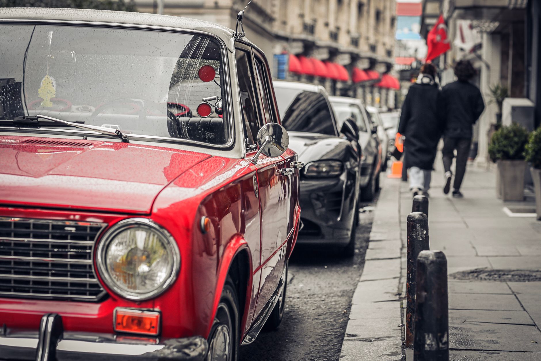 Voiture ancienne rouge garée dans une rue pavée